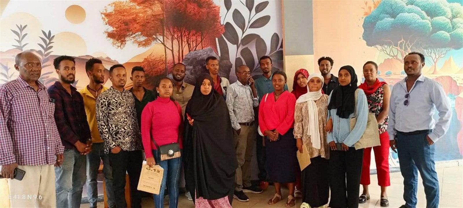 Group photo of the first facilitators meeting against a painted mural backdrop