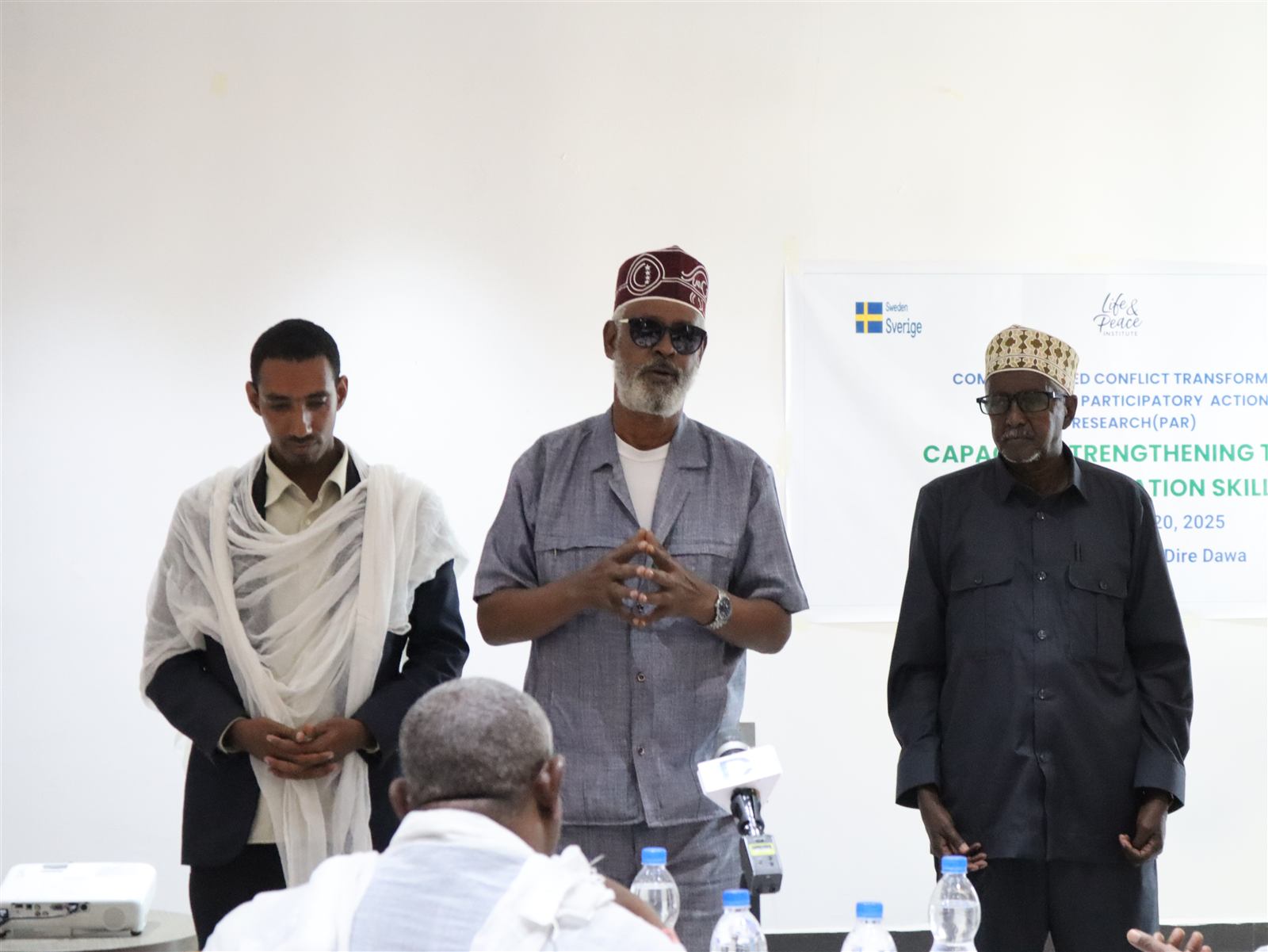 Panel of community and religious leaders standing at the front of the training room