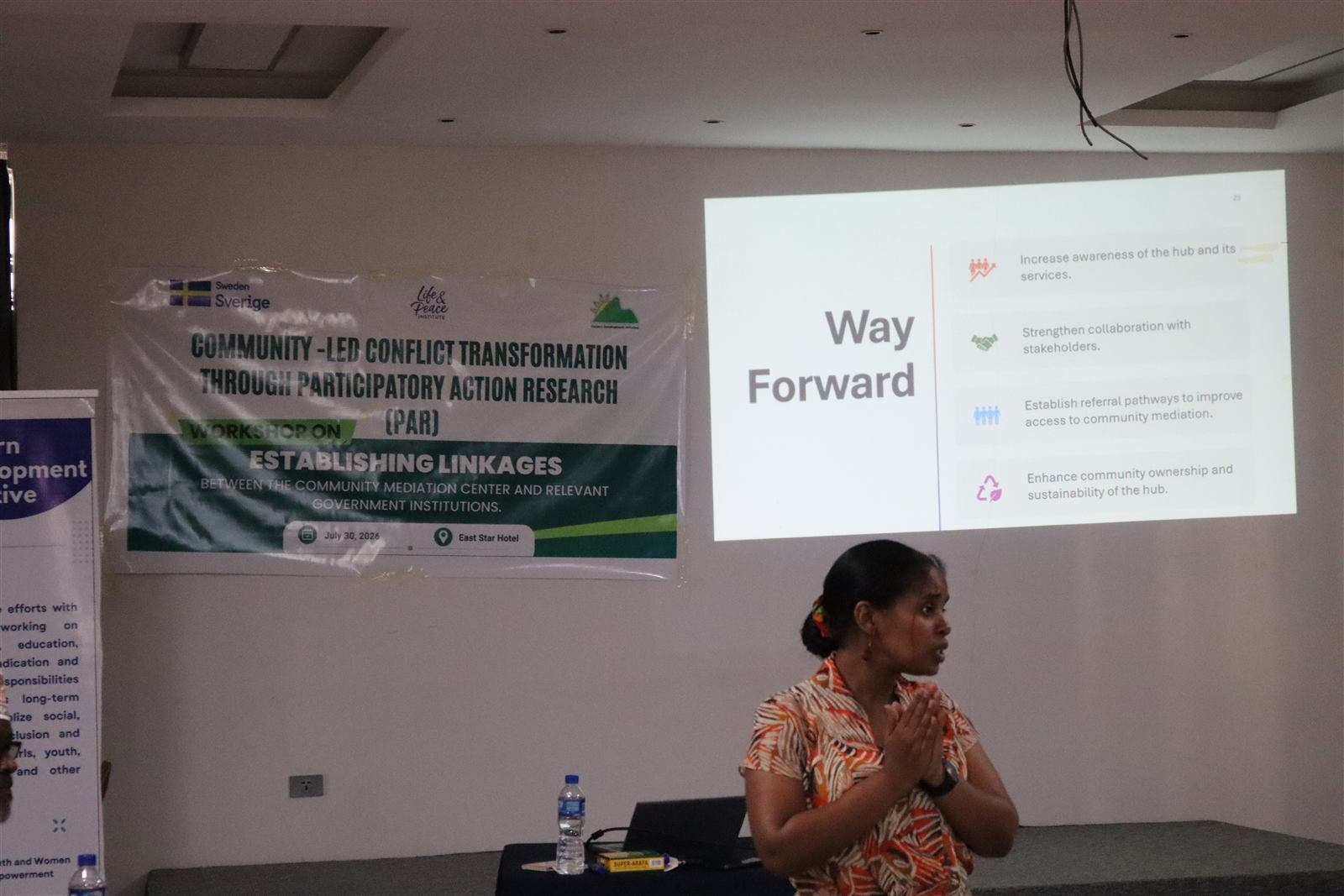 Workshop banner on establishing linkages between the community mediation center and government institutions, beside a Way Forward slide