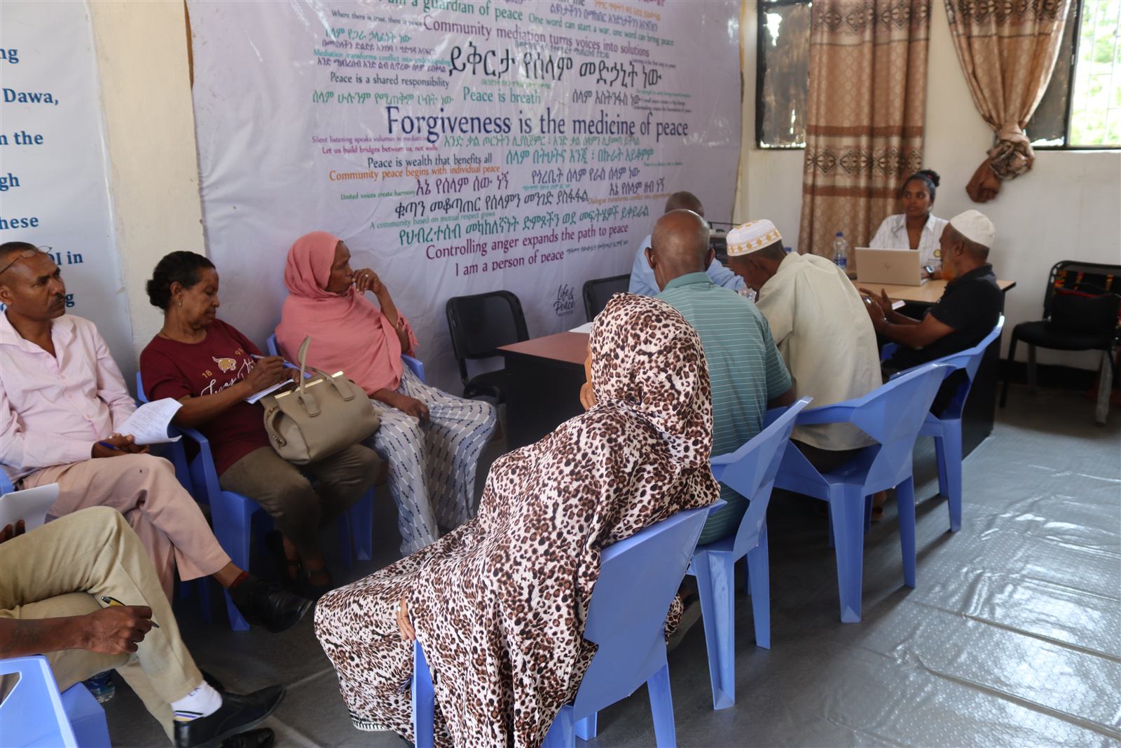 Mediation hub members in session beneath a wall of peace affirmations