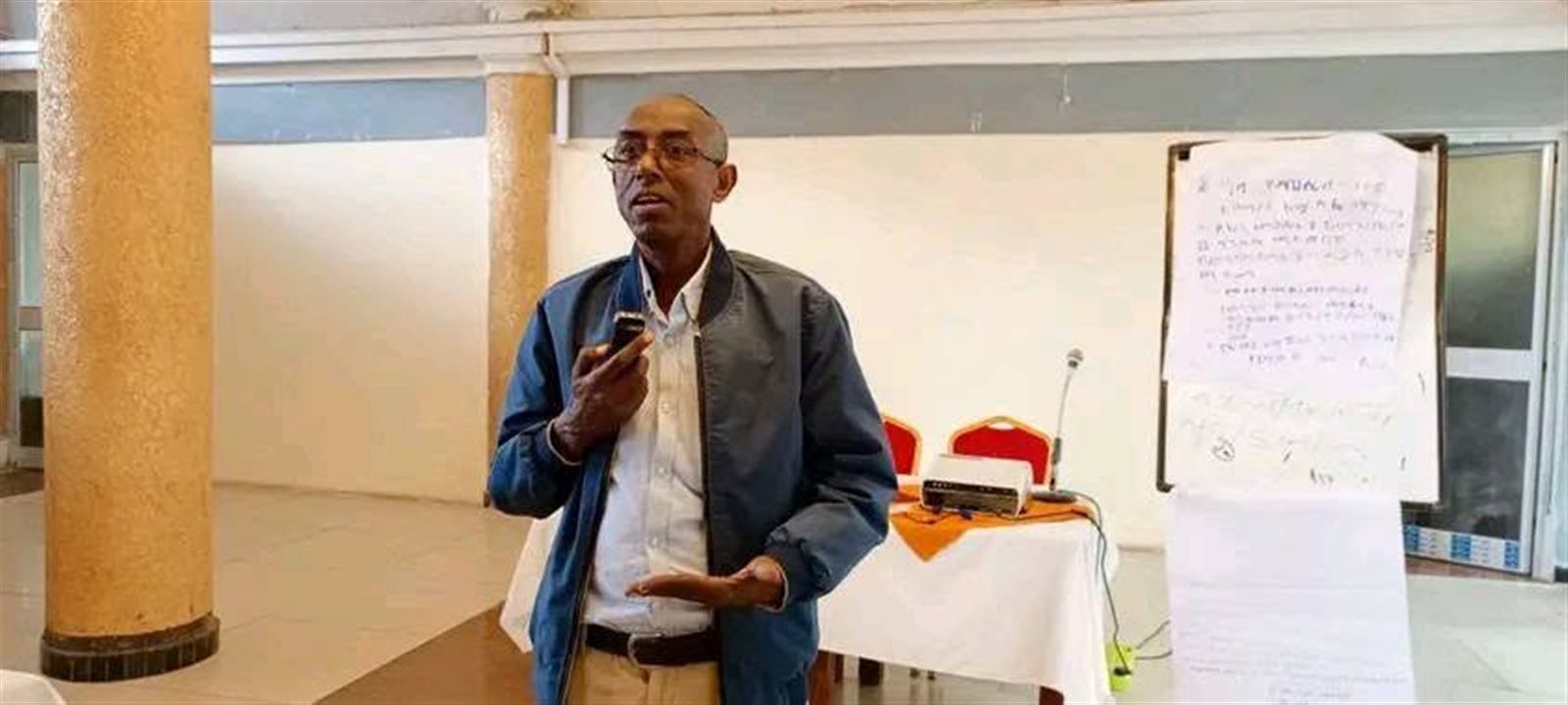 A participant speaking beside handwritten Amharic flip-chart notes