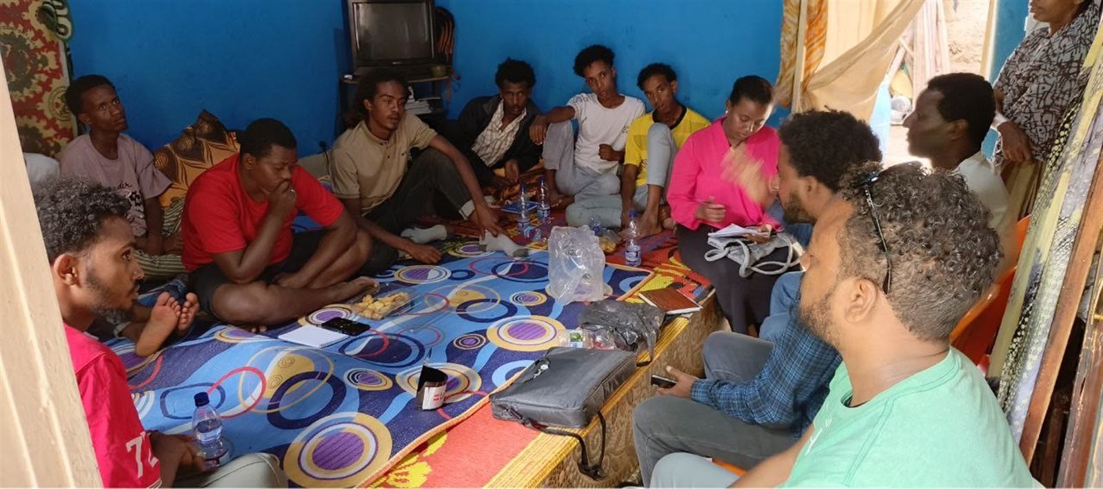 Group seated on a patterned rug in an informal community discussion