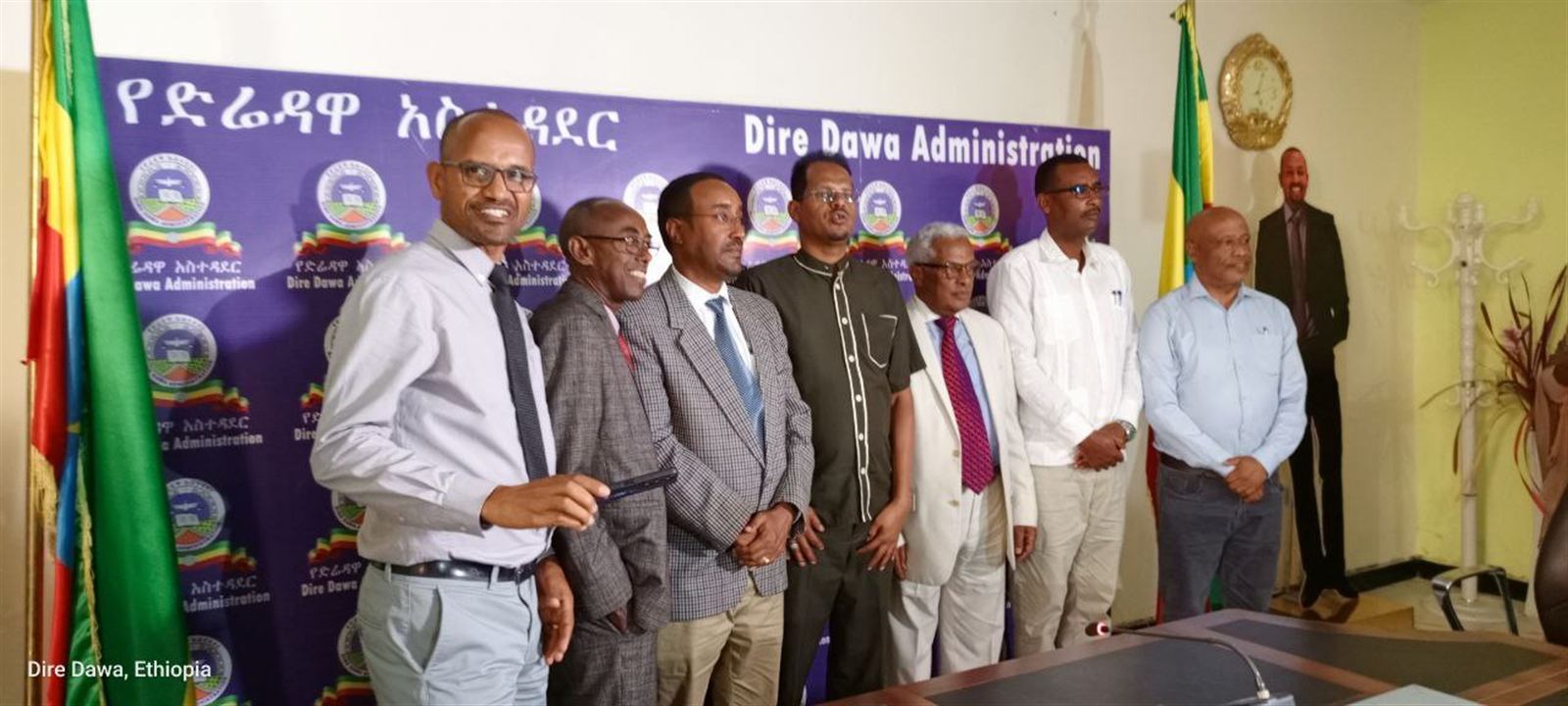 Officials posing formally in front of an official Dire Dawa Administration backdrop with Ethiopian flags