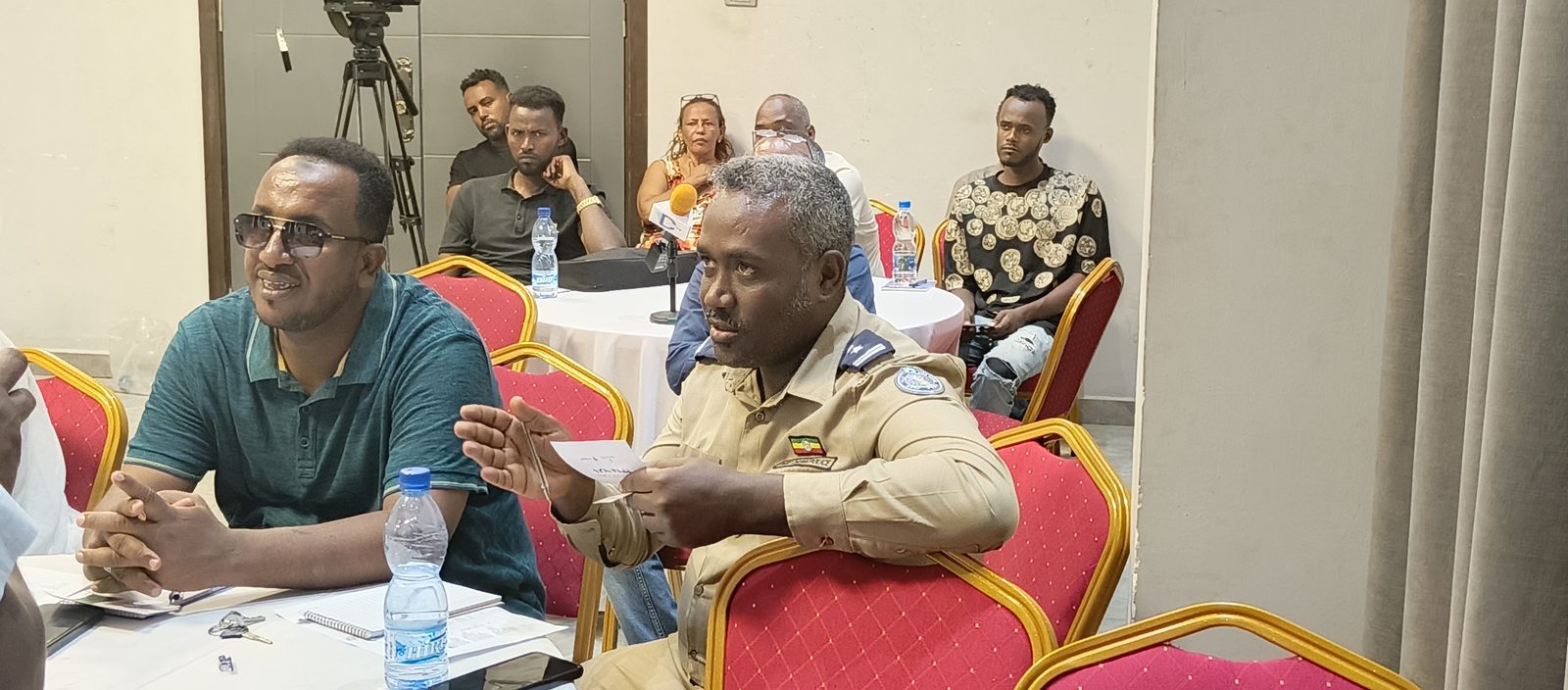 A Dire Dawa police officer in uniform speaks during the review meeting, holding a discussion note card