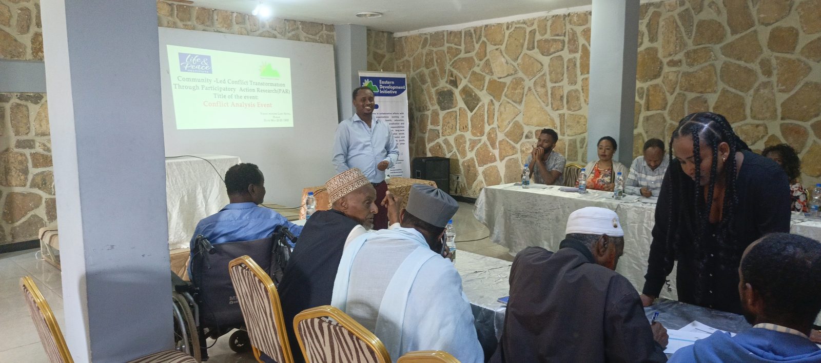 Presentation slide titled Conflict Analysis Event, Wonderland Hotel, Harar, with a wheelchair-using participant in the front row