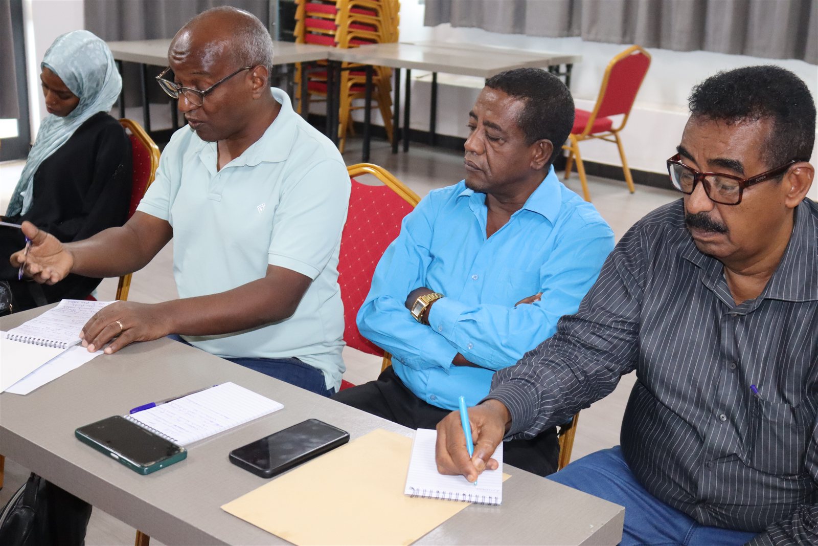 Facilitator speaking in front of the banner for the 1st Round Quarterly Review Meeting with Stakeholders, May 20 2026, East Star Hotel