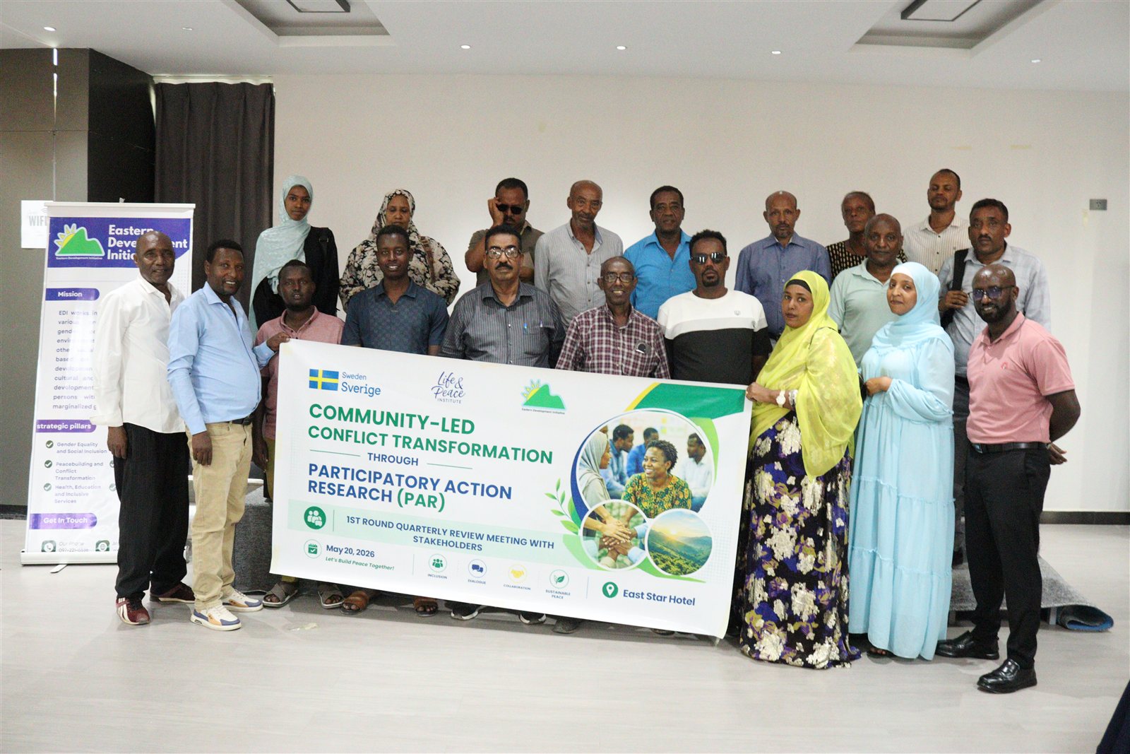Closing group photo of about nineteen participants and staff holding the event banner