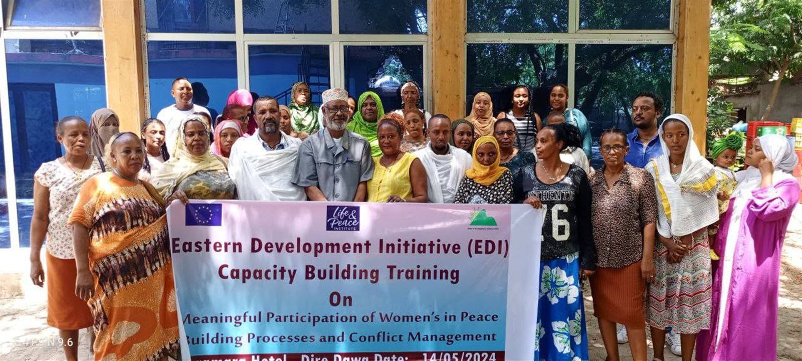 Large mixed group of about thirty people posed outdoors holding the Capacity Building Training banner, May 14 2024