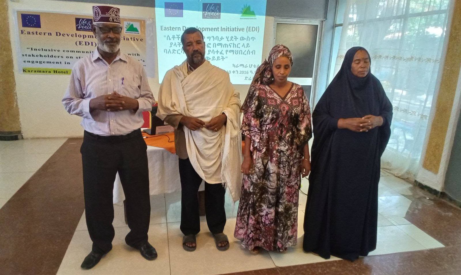 Four people standing before a projected bilingual English and Amharic closing slide