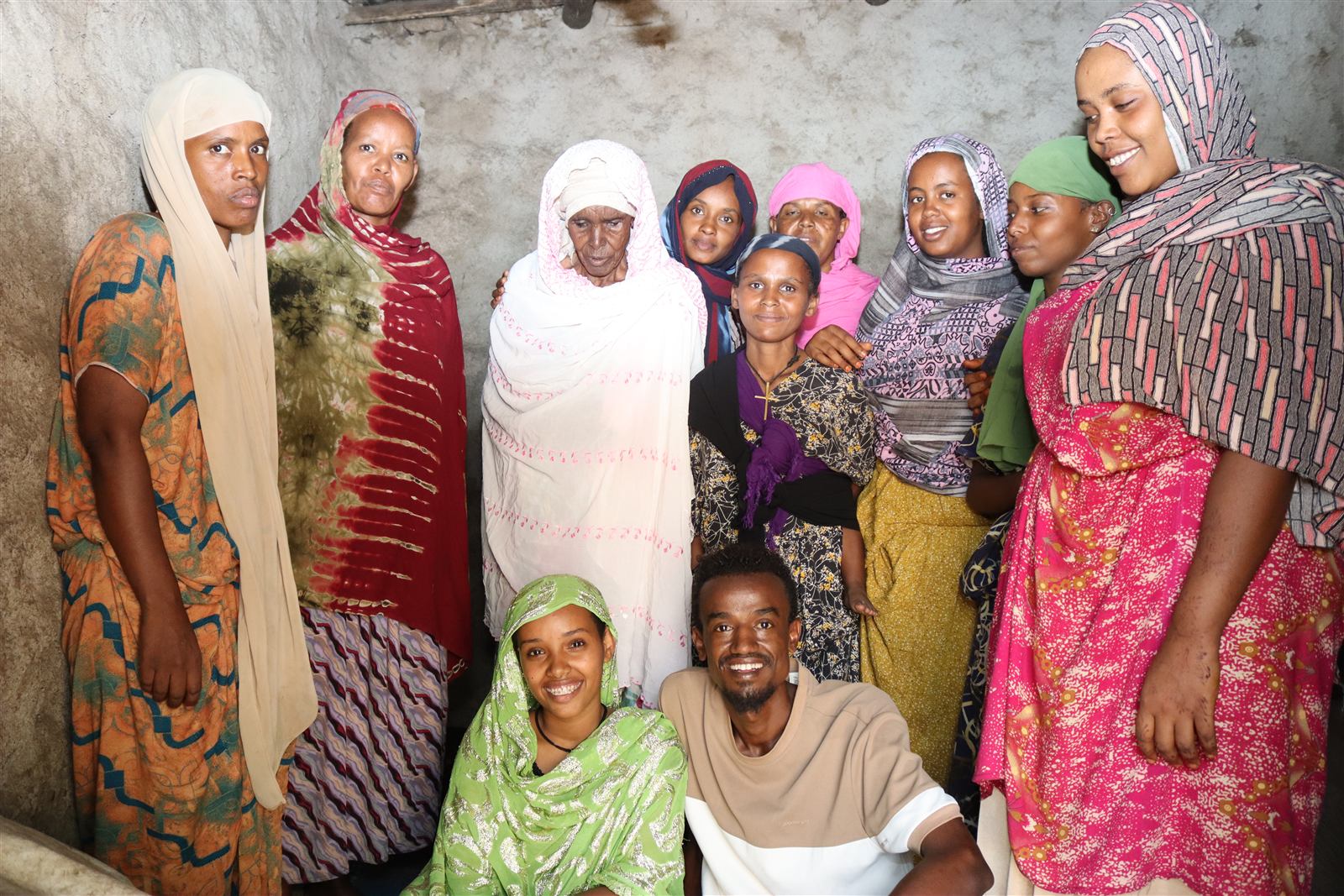 A women's group standing with an elderly neighbor, arms around her, smiling